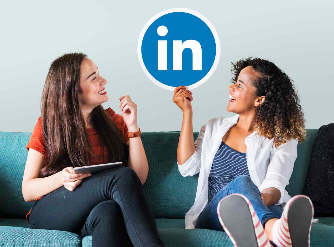 Profesional actualizando perfil de LinkedIn en portátil en oficina en casa con estanterías y luz de tarde