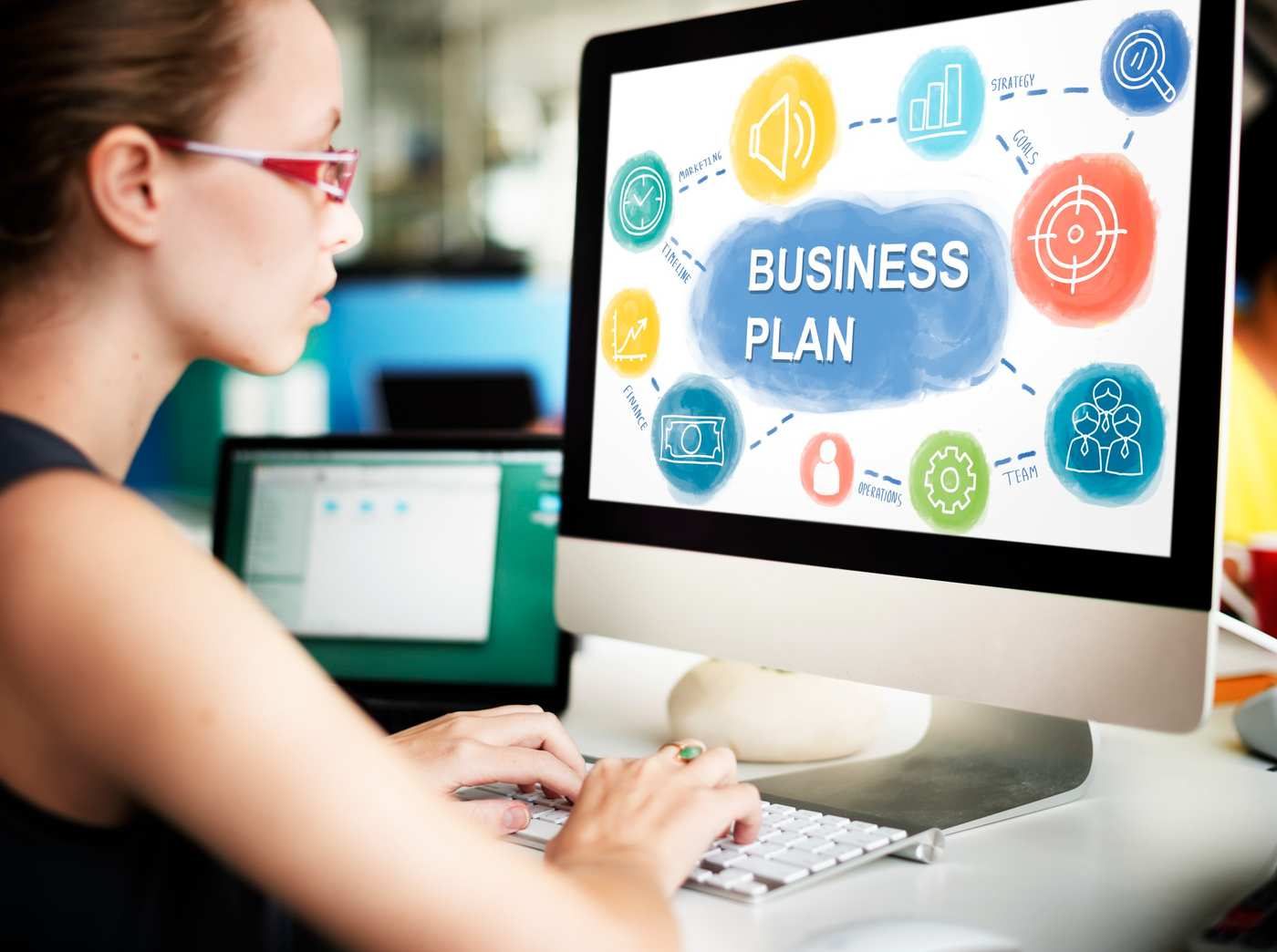 Propietaria de pyme en Vitoria planificando estrategia de marketing digital en cuaderno con portátil y café en mesa