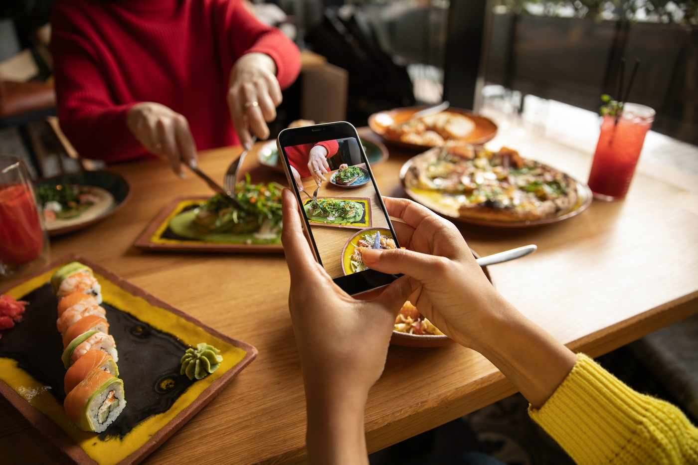 Dueño de restaurante vasco mirando analíticas de redes sociales en smartphone en mesa con platos tradicionales vascos