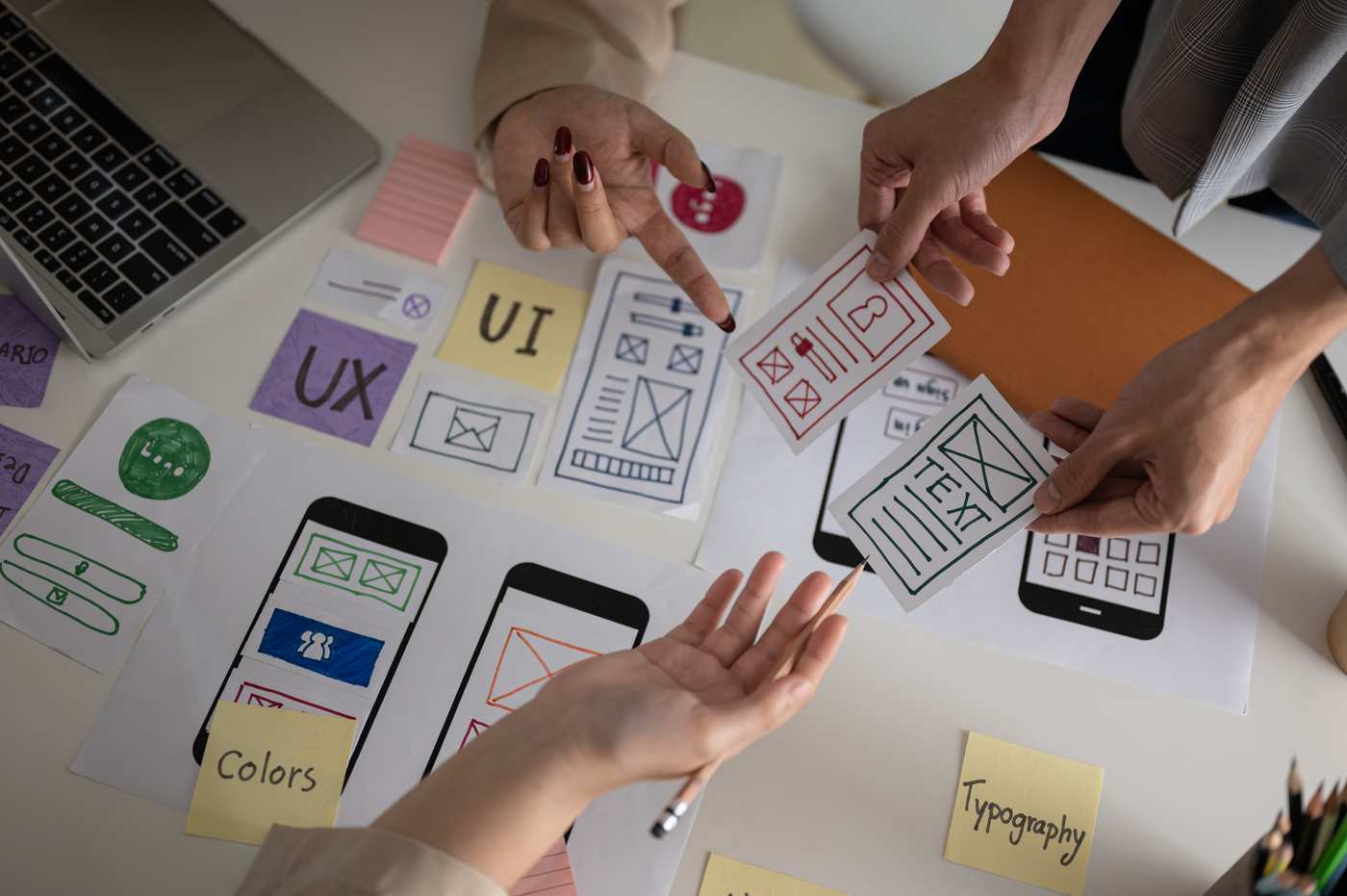 Diseñador UX trabajando en wireframes de web en portátil con stylus pen en escritorio minimalista blanco